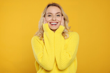 Canvas Print - Happy woman in stylish warm sweater on orange background