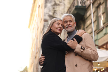 Affectionate senior couple dancing together on city street, low angle view. Space for text