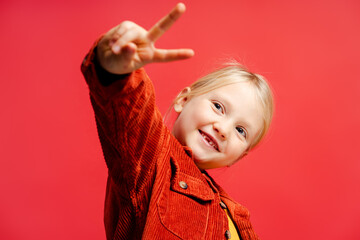 Wall Mural - Portrait of cute little girl wearing yellow hat and casual clothes, showing victory sign