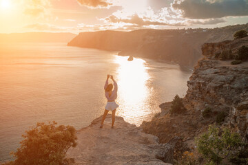 Wall Mural - Free girl with open arms at sunset over the sea, sun over clouds, sunset in the mountains, golden hour, silhouette of a woman at sunset on the mountain
