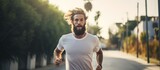 Fototapeta  - Fit Caucasian 20s hipster guy jogging, prioritizing a healthy lifestyle and fitness goals, training his body and physical strength through morning cardio workouts.
