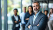 © Kowit - Cheerful businessman standing with arms folded in front of colleagues