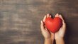 Hand hold red heart on brown background. Concept donation helps find loving health care