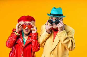 Wall Mural - Beautiful senior old couple wearing fancy party clothes acting in studio on a colored background. Conceptual image about third age and seniority, old people feeling young inside.