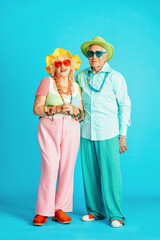 Wall Mural - Beautiful senior old couple wearing fancy party clothes acting in studio on a colored background. Conceptual image about third age and seniority, old people feeling young inside.