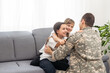 © Angelov - happy positive smiling soldier man in camouflage sitting with his daughter on sofa, looking how his kid grown when he was in army, returning home from war.
