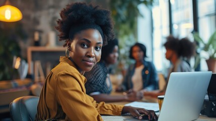 Wall Mural - Young African American female businesswomen start-up looking camera working with colleagues partners sitting in cozy workplace meeting room, modern home office with technology laptop computer on table