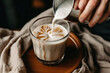 The Art of Latte. A skilled hand pours steamed milk into a coffee glass, creating an intricate latte art pattern on a warm and cozy backdrop