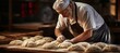 Skilled baker kneading dough in bakery for baking bread   blurred background with copy space