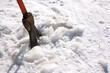 human clears the yard from the ice with a sharp orange-colored iron cleaver, on a bright sunny frosty winter day. landscaping of the yard. Snow removal
