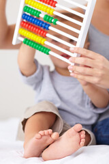 Canvas Print - Abacus, math and baby with mother playing, learning and teaching for child development on bed. Bonding, toy and closeup of mom with kid, infant or toddler with counting together in bedroom at home.