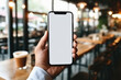 Cropped image of a man holding mobile phone with blank screen in cafe