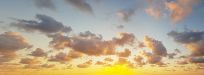 Wall Mural - orange dawn sky. dramatic sunrise with dark cloud, gold sun and blue sky. panoramic nature backgroun