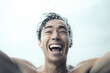 Close-up male portrait of a young attractive asian man laughing and splashing water