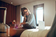 © Marko Geber - Businessman talking on phone call and using laptop in hotel room