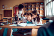 © Marko Geber - Little girls whispering to each other in classroom