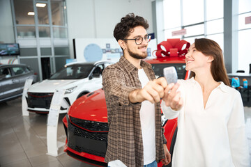 Wall Mural - Happy woman and man showing automobile keys celebrating buying new car