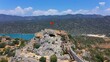 Simena castle in Kalekoy and Turkish flag waving in hot summer breeze. Amphitheater with 7 rows of seats carved into rock in the castle, can host 300 people, smallest theater among the Lycian cities