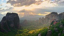 Meteora Greece. Sunset Sun Rays Through Sky Clouds In Mountain Valley
