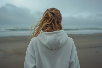 Poster - A woman standing on a beach, gazing out at the vast expanse of the ocean. Perfect for travel brochures or inspirational content