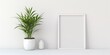 © Fotograf - A picture frame hanging on a wall next to a vibrant potted plant. Perfect for adding a touch of nature to any space