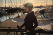 Portrait of beautiful female cyclist wearing cycling kit, glasses and helmet during sunset on yucht club background. Healthy lifestyle concept.  Workout and favorite hobby. Cycling advanture in Spain.