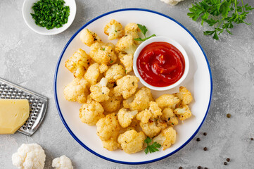 Wall Mural - Baked cauliflower with parmesan cheese on a gray concrete background. Vegetarian healthy food.