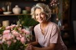 © duyina1990 - Portrait of a smiling middle-aged woman with short blonde hair standing in front of a table with pink flowers
