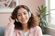 © Portrait Studio - A smiling teenage girl, wearing headphones, engages in online learning, showcasing the concept of studying in a virtual classroom while participating in an online class through webcam
