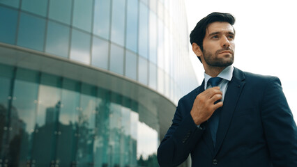 Wall Mural - Landscape image of business man adjust tie while standing at building. Project manager wearing suit while looking around the city. Executive manager check himself before going to interview. Exultant.