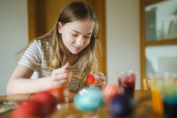 Wall Mural - Pretty teenage girl dyeing Easter eggs at home. Child painting colorful eggs for Easter hunt. Kid getting ready for Easter celebration.