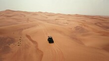 Tourist Driving A Dune Buggy In Dubai Desert Dunes, Aerial View On A Hot Summer Day