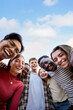 © CarlosBarquero - Vertical portrait group multiracial friends posing smiling and looking to camera. Happy young people hugging together standing outdoors. Generation z guys and girls enjoying spring vacation day