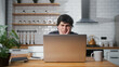 © mahirkart - Sad young man sitting against the kitchen using laptop having anxiety and stress. Upset man reacting to loss, bad news