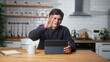 © mahirkart - Smiling young man sitting in the modern kitchen having video call conversation through using tablet computer. Share news, talk to family, enjoy webchat virtual meeting