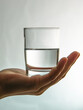 Hand showing a conceptual half-full glass of water