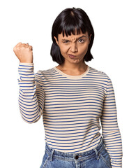 Wall Mural - Young Hispanic woman with short black hair in studio showing fist to camera, aggressive facial expression.