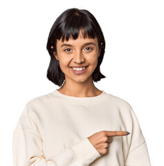 Young Hispanic woman with short black hair in studio smiling and pointing aside, showing something at blank space.