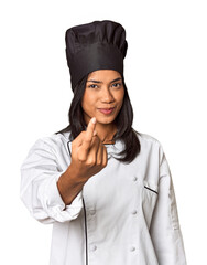 Wall Mural - Young Filipina chef with cooking hat in studio pointing with finger at you as if inviting come closer.