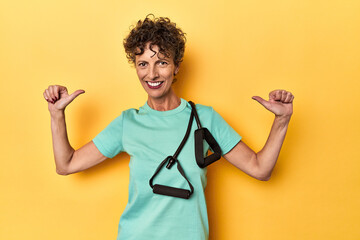 Wall Mural - Sportswoman with resistance bands on yellow feels proud and self confident, example to follow.