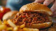 Close-up of a sloppy joe sandwich with a side of fries