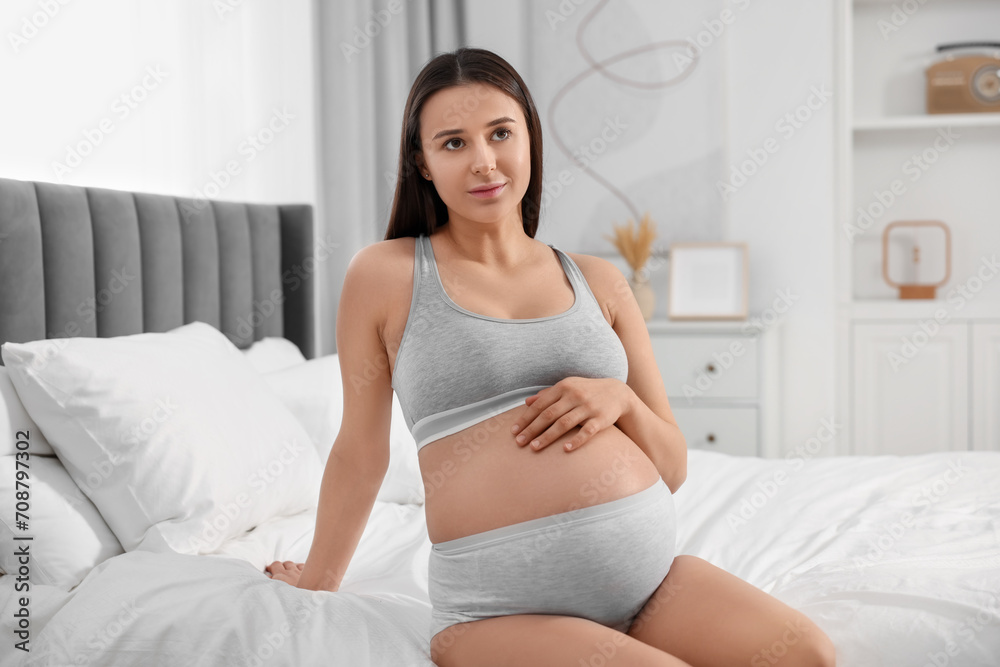 Beautiful pregnant woman in comfortable maternity underwear on bed at home