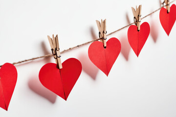 Garland of red paper hearts hanging on a string, isolated on a white background. Romantic and love concept. Valentines day background for design greeting card, banner, flyer, poster