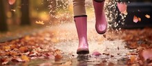 Woman In Pink Boots Jumps In Puddle On Autumn Day.