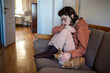 Depressed exhausted teen girl in glasses pyjamas petting cat sitting on couch at home in closed pose. Teenage age crisis, emotional burnout depression, psychological or life problems troubles concept.