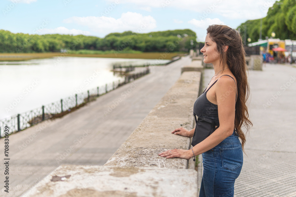 Young woman standing on the waterfront looking at the river with a lost ...