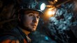 A thoughtful miner with a lit headlamp looks off into the distance, contemplating the vast and challenging work environment of the mine.