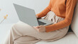 © Breezze - Woman in a soft peach sweater using a laptop on her lap, embodying the comfort of slow living and the joy of simple technology in a serene setting