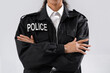 African-American female police officer with crossed arms on white background