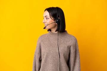 Wall Mural - Young telemarketer woman isolated on yellow background looking side